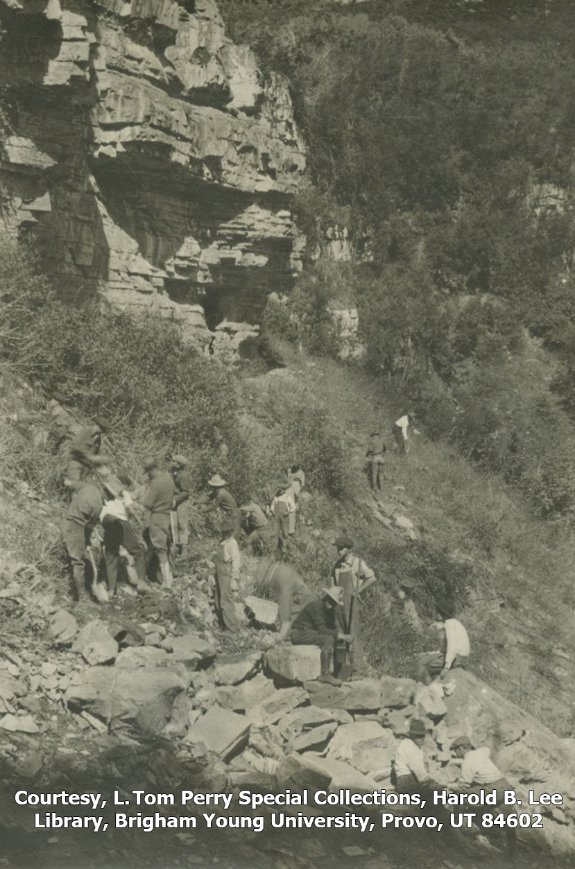 Men are shown bending over and moving rocks along a trail they are building in this black and white photo.