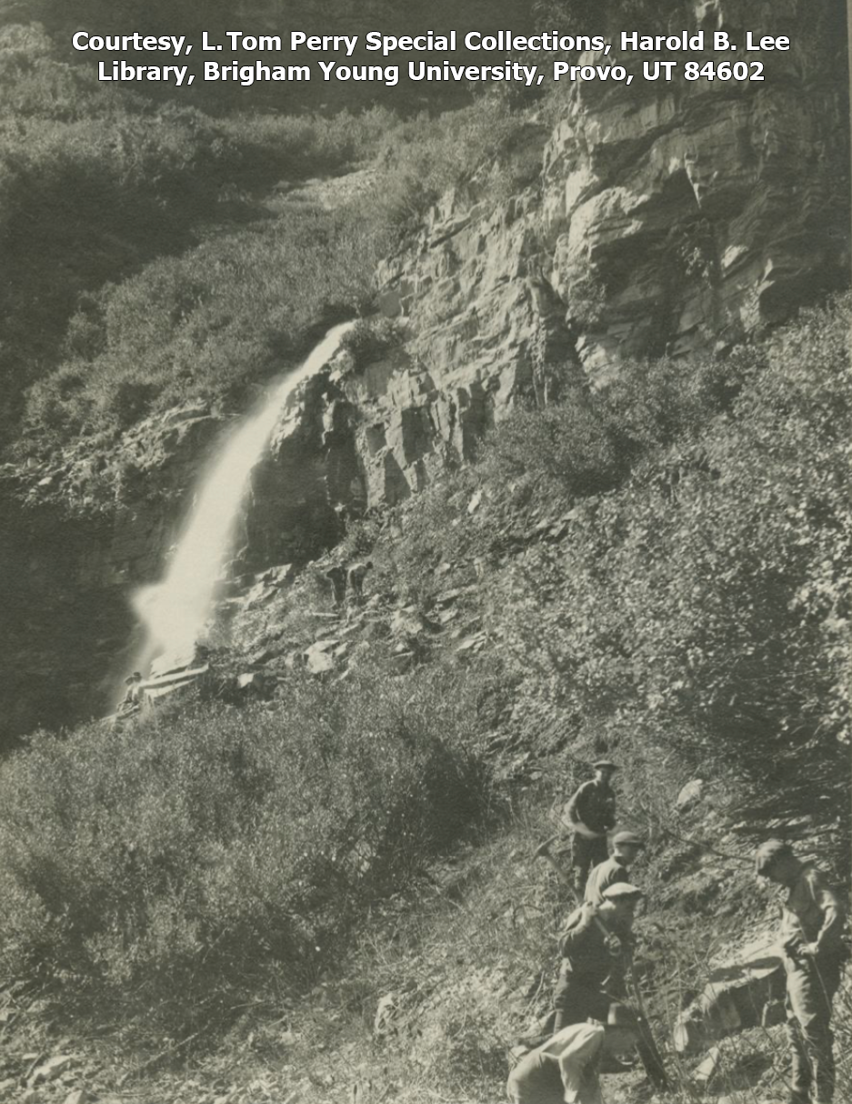 Men are shown building a trail with a waterfall in the background in this black and white photo.