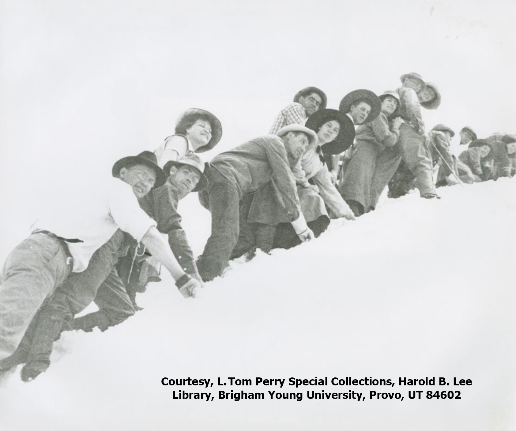 A group of students from the first summit hike are shown climbing a hill covered in snow in this black and white photo