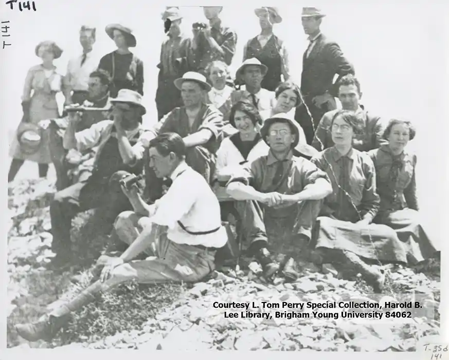 A group of hikers sits together on the summit of timpanogos in this black and white photo